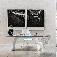 Modern office setting with sleek white furniture, glass tabletop, and black-and-white wall art. Minimalist design elements.