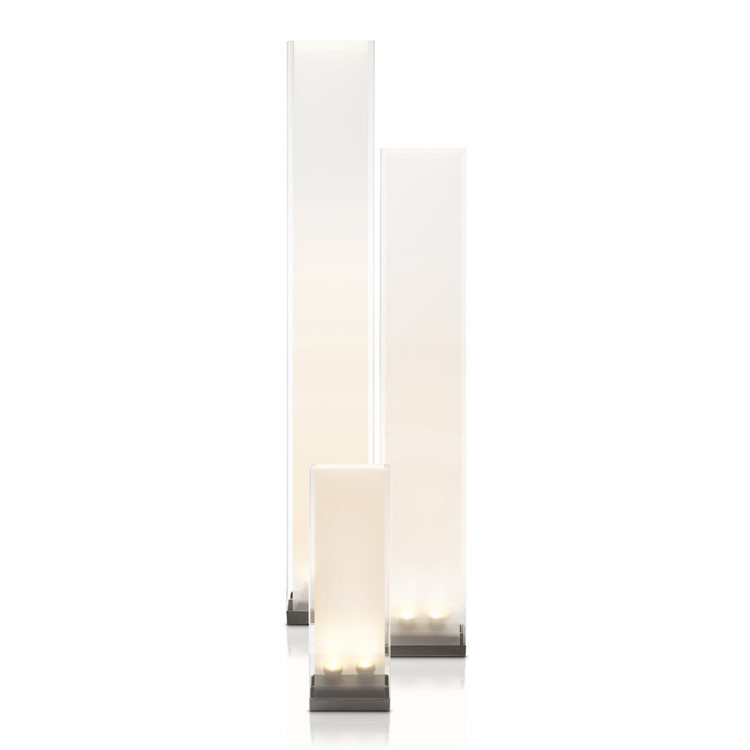 Three sleek, tall lamps with a smooth white finish and soft glowing base, set on a minimalist metal stand.