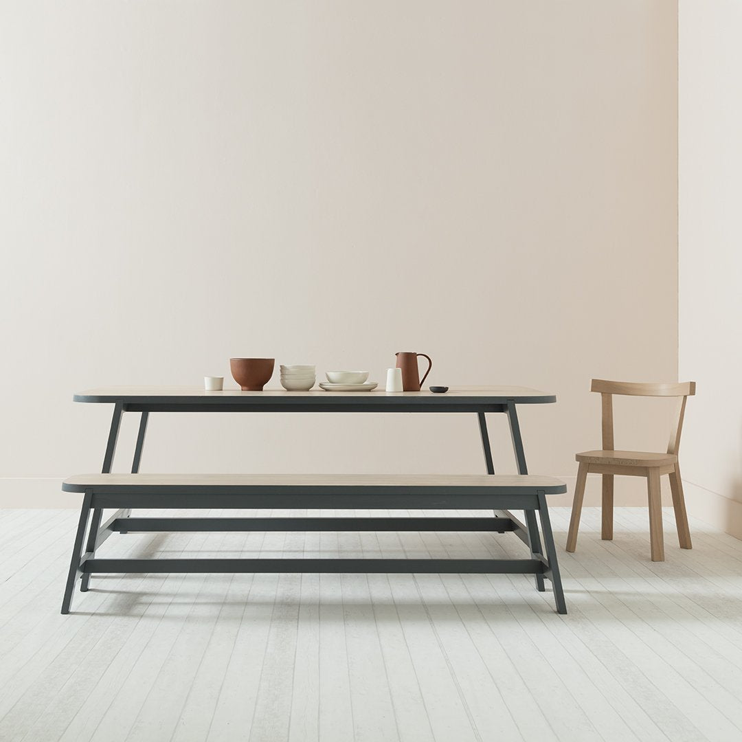 Modern gray picnic table with natural wood accents, set against a soft pink wall and light wood floor.