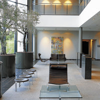 Modern lobby featuring neutral tones, abstract colorful artwork, and sleek black and glass furniture.