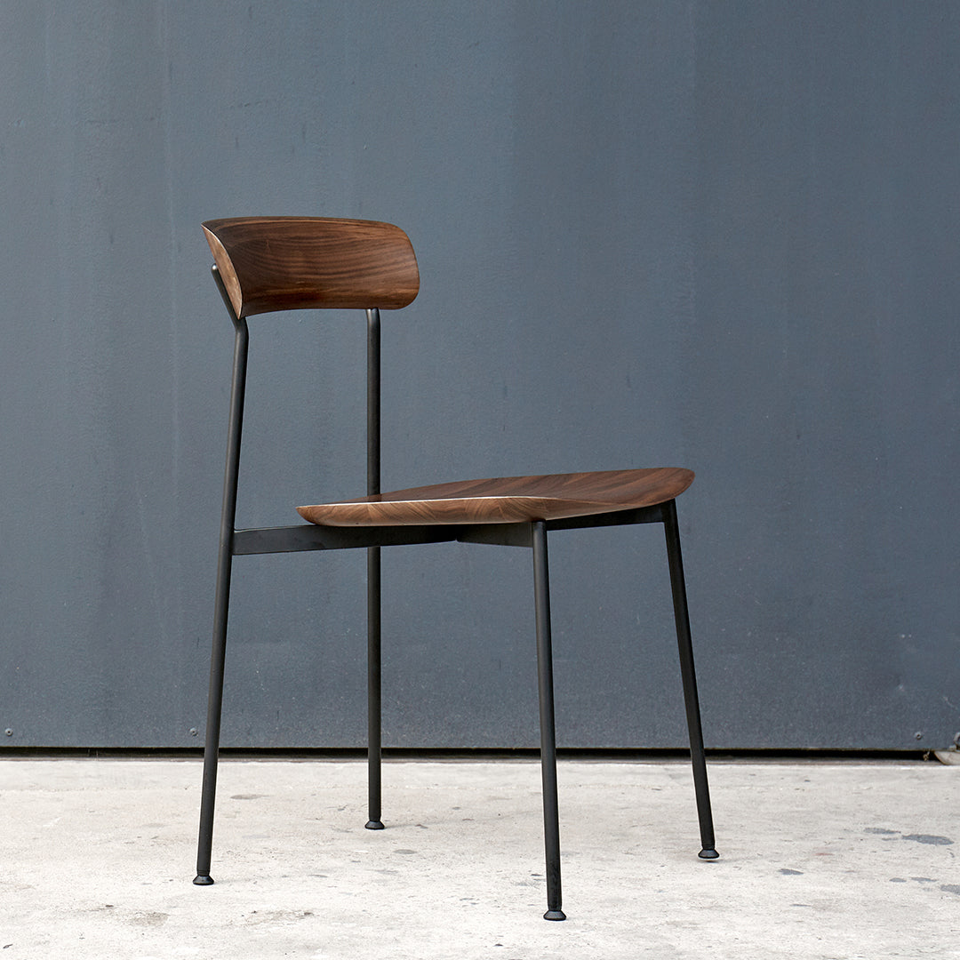 Modern wooden chair with a rich, dark finish and sleek black metal legs against a gray background.