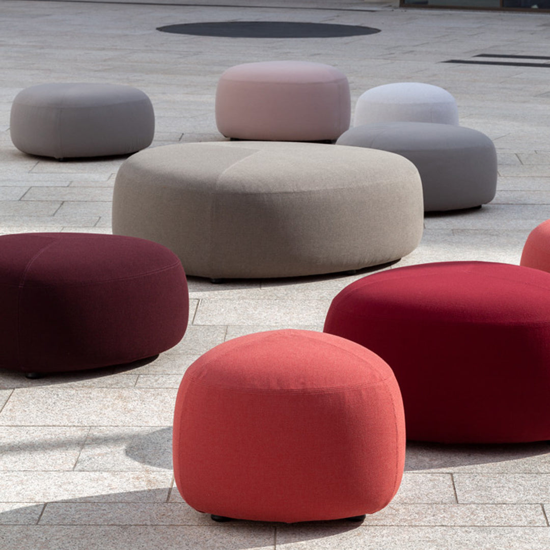 Colorful poufs featuring soft hues of pink, gray, burgundy, and coral in various round shapes and sizes.