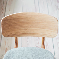 Light wooden chair back with natural grain, paired with soft blue upholstery for a modern, minimalist look.