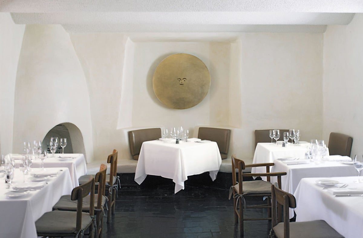 Elegant white tables with white linen, soft gray chairs, and minimalist decor against a neutral backdrop.