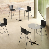 Modern black bar stools and matching table on a neutral-toned floor with minimalist design elements.
