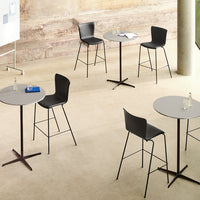 Set of gray tables with black chairs in a minimalist indoor setting, featuring sleek lines and modern design.