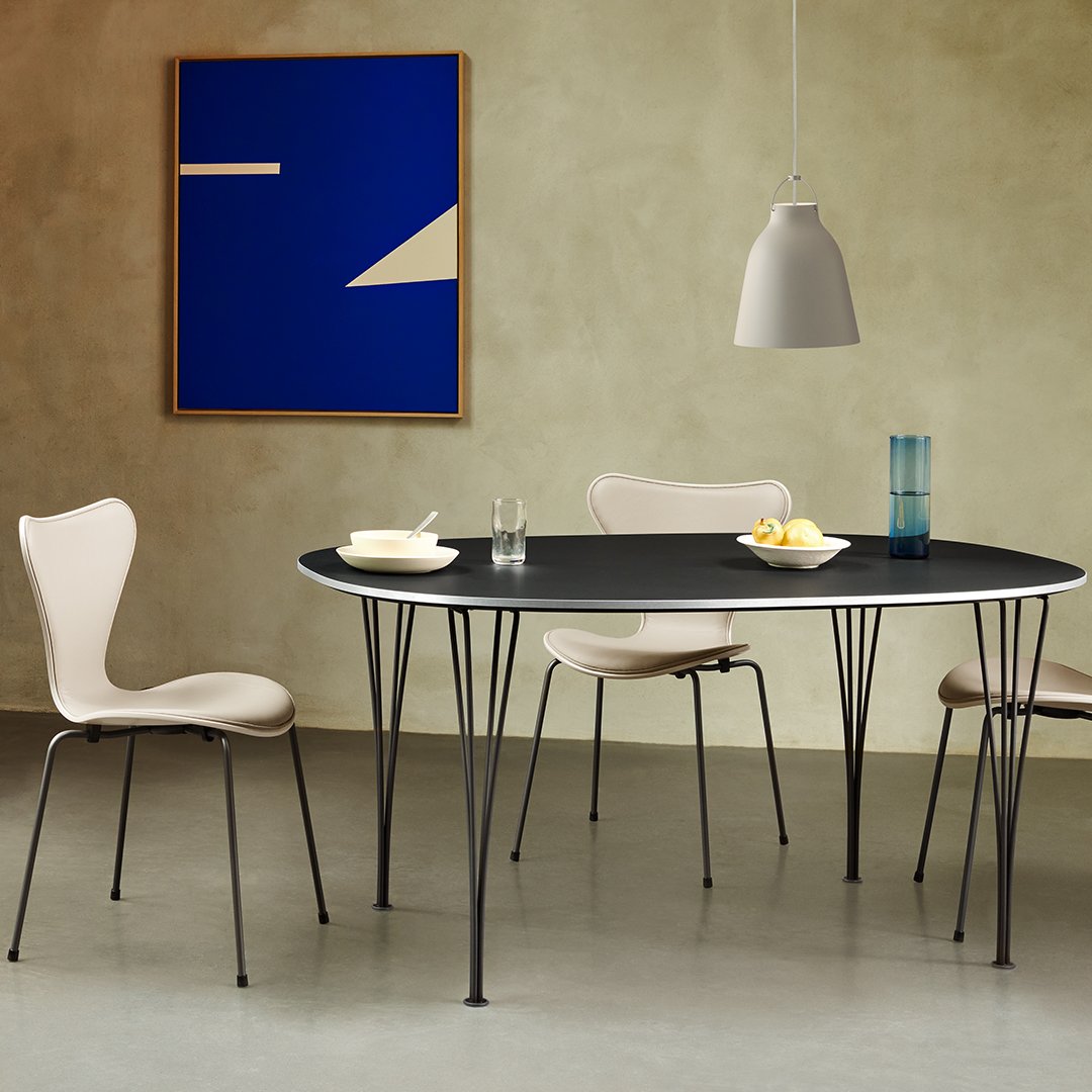 Modern black oval table with light beige chairs, set against a textured beige wall and a bold blue abstract art piece.