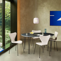 Elegant black round dining table with white chairs, modern design, and neutral green and blue accents in a contemporary setting.
