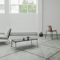 Modern room with light gray flooring, contrasting black coffee table, and soft pink chair, featuring minimalist patterns.