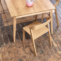 Light wood dining table with simple, modern design; natural finish, paired with a matching wooden chair.