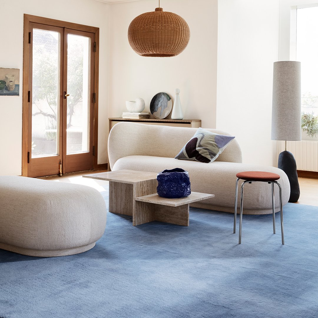 Light blue area rug with soft, textured patterns, accentuated by cream and natural wood furnishings in a bright room.