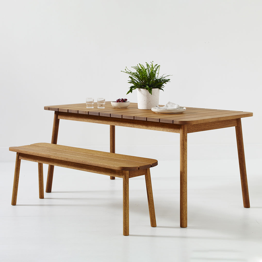 Natural wood dining table and bench with a smooth finish, featuring a simple, minimalist design and light brown tones.