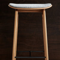 Wooden bar stool with a light natural finish and a gray textured seat, showcasing modern minimalist design.
