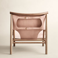 "Light wood chair with soft pink leather straps and a minimalist design, featuring smooth curves and subtle patterns."