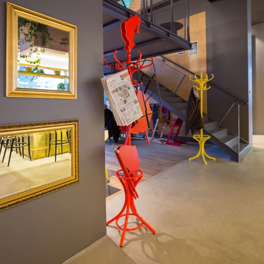 "Vibrant red and yellow coat racks against a modern gray interior, with elegant mirrors reflecting stylish decor."