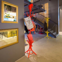 "Vibrant red and yellow coat racks against a modern gray interior, with elegant mirrors reflecting stylish decor."