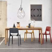 Modern dining set featuring grey, yellow, red, and clear glass elements against a minimalist background.