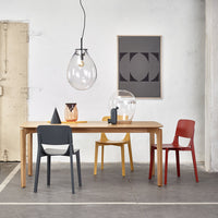 "Modern dining setup featuring gray, yellow, red, and clear glass elements with geometric patterns on the wall."