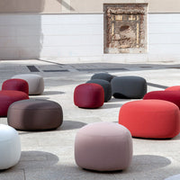 Colorful round poufs in shades of red, gray, white, and brown, featuring a soft, smooth texture.
