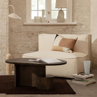 Beige couch with geometric brown and cream cushions, dark wood coffee table, and neutral decor in a minimalist room.