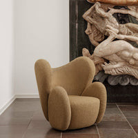 Curved tan chair with soft, textured upholstery against a dramatic stone mural backdrop. Stylish and contemporary design.