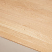 Light natural wood tabletop with smooth, subtle grain patterns, showcasing a warm, minimalistic design.