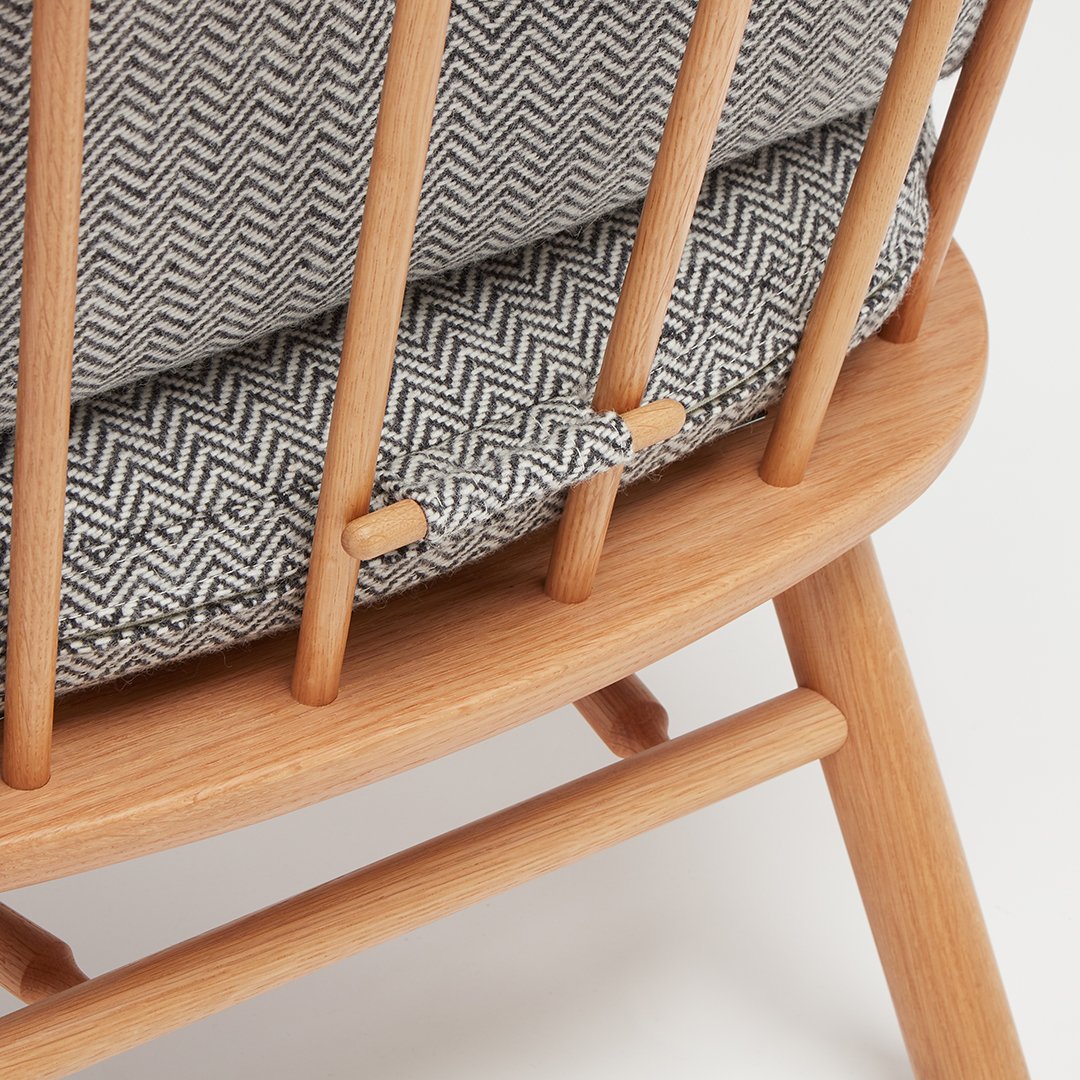 Modern wooden chair featuring a gray chevron-patterned cushion and natural wood finish for a stylish look.