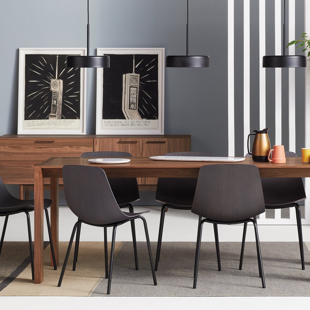 Modern dining room featuring dark wood furniture, sleek black chairs, gray walls, and bold black and white artwork.