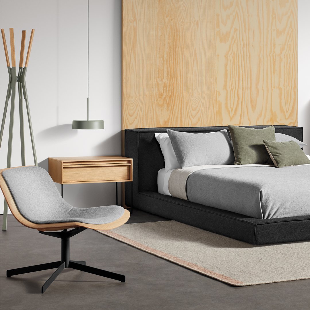 Modern bedroom featuring gray bedding, a sleek black bed frame, and a stylish light gray chair with wooden accents.