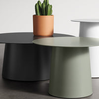 Three modern side tables in matte black, olive green, and white, accompanied by a terracotta planter with a cactus.