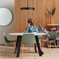 "Round white table with black legs, green chairs, and zebra-striped leggings in a modern wooden interior."