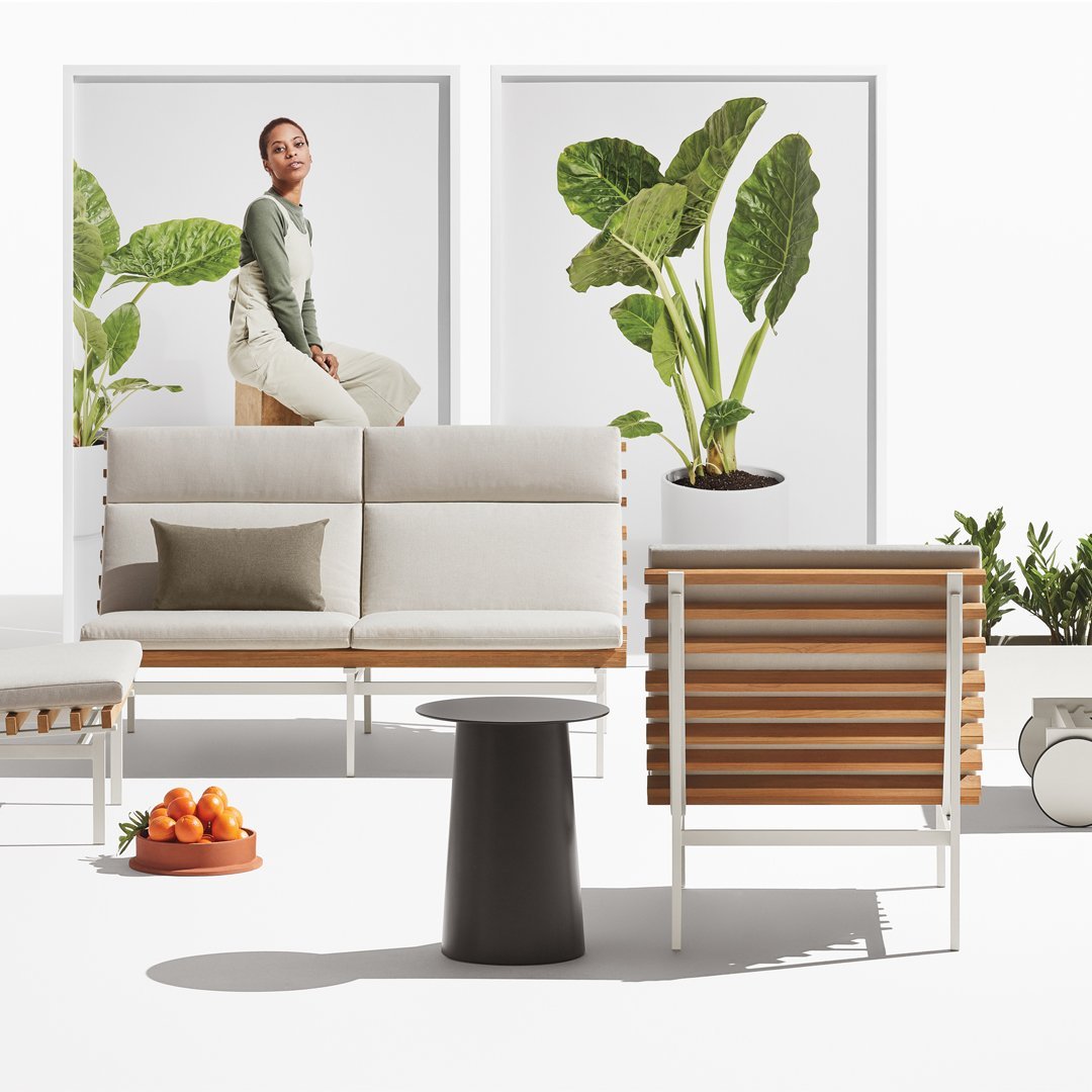 Modern outdoor furniture set featuring neutral tones, natural wood, and lush green plant accents. Contemporary design elements.