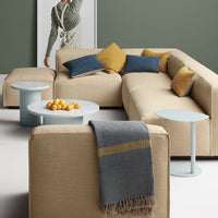 Beige sectional sofa with blue and mustard pillows, paired with light blue side tables and a textured gray throw blanket.