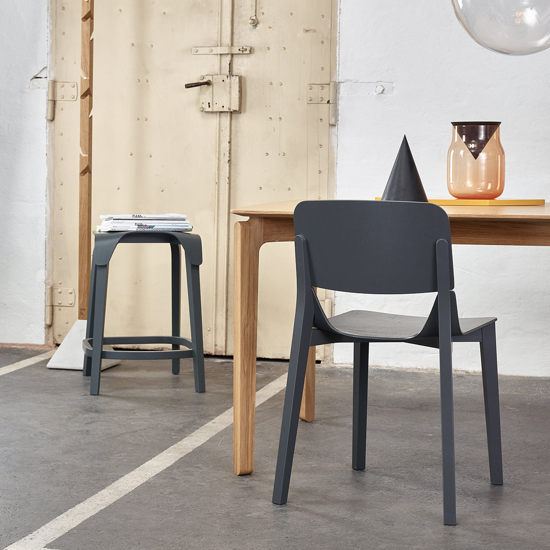 Modern gray chair with sleek design, paired with a minimalist wooden table and decorative accents in warm tones.