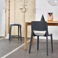 Modern gray chair with sleek design, paired with a minimalist wooden table and decorative accents in warm tones.