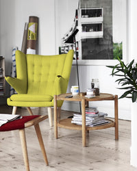 Bright lime green wingback chair with tufted design, paired with a wooden accent table and natural decor elements.