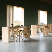 Modern wooden bar tables with natural finish, light beige tones, and minimalist design against a dark green wall.