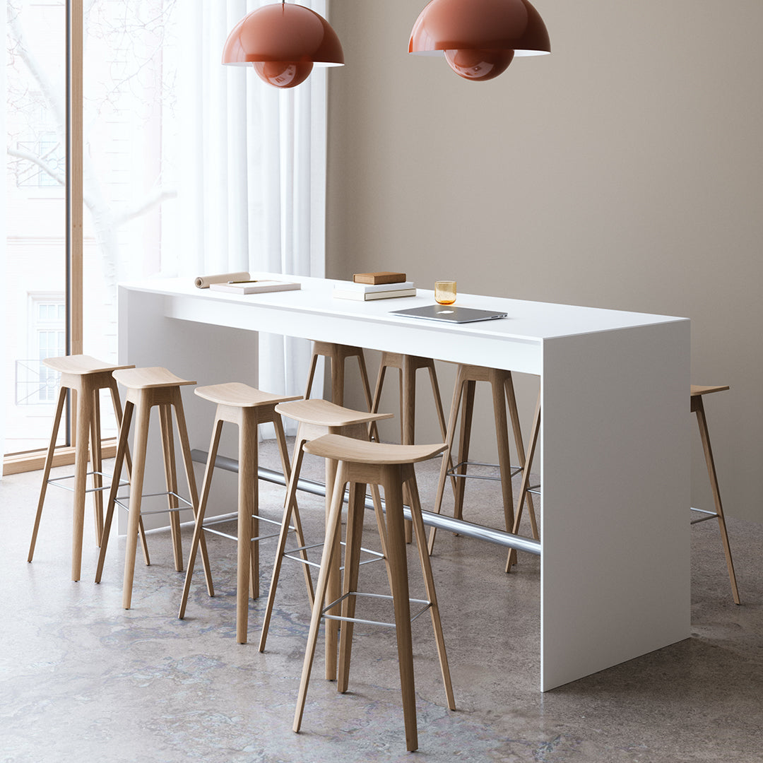 Minimalist white bar table with natural wood chairs, accentuated by warm, terracotta pendant lamps.