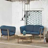 Blue upholstered sofa set with a modern geometric pattern in the background and natural wood accents.