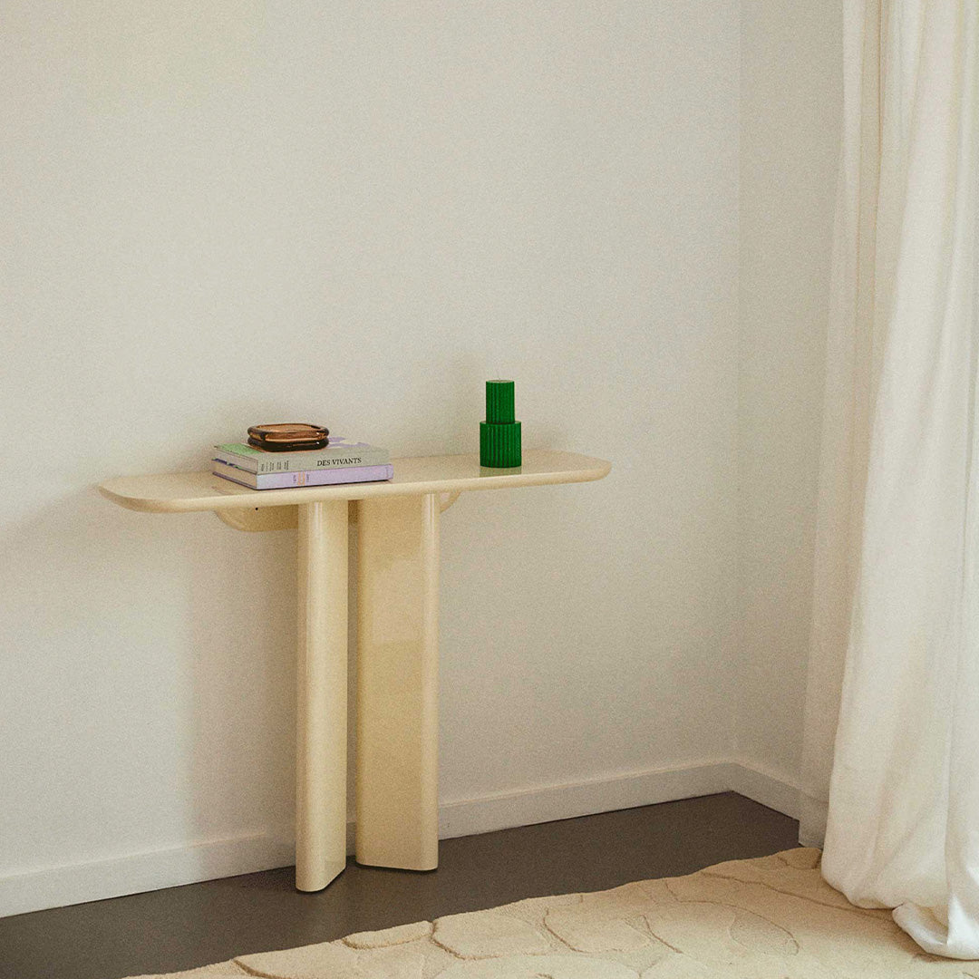 Modern beige console table with simple lines, featuring a green vase and layered neutral textures.