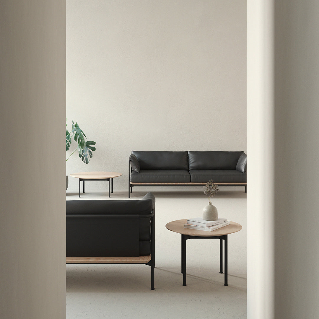 Modern black leather sofa with minimalist wood accents and neutral tones in a stylish interior setting.