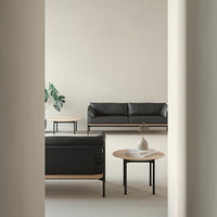 Modern black leather sofa with minimalist wood accents and neutral tones in a stylish interior setting.