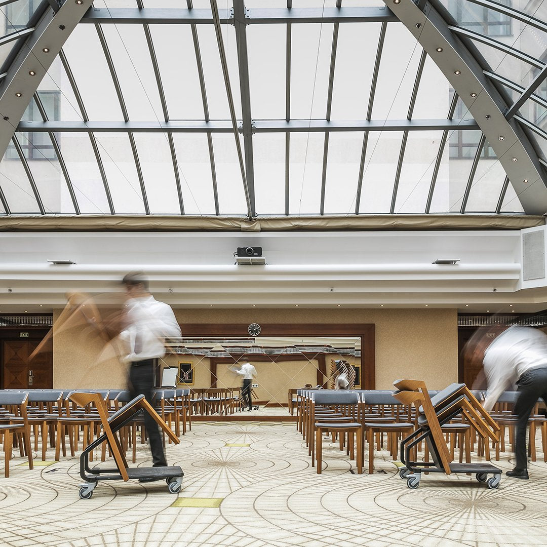 "Stylish wooden chairs against a soft beige background with geometric patterned flooring and a bright skylight."