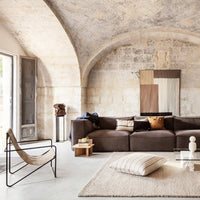 Brown sectional sofa with earthy tones, beige geometric patterns, and a light neutral rug for a modern, chic look.