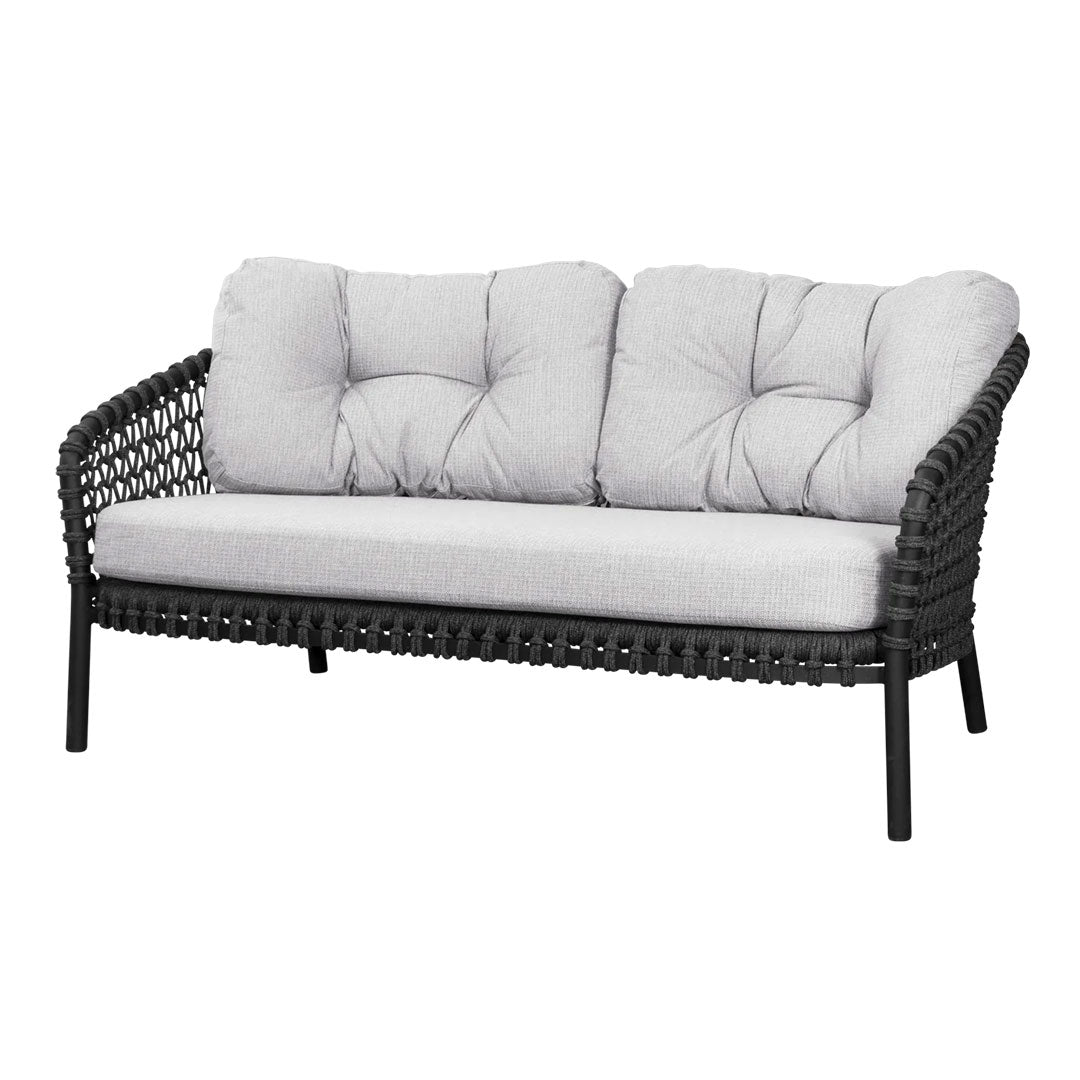 Black woven outdoor sofa with plush light gray cushions and tufted detailing. Stylish and modern design for outdoor spaces.