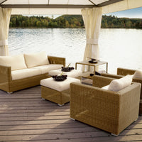 Beige wicker seating set with cream cushions, featuring a simple, elegant design against a serene water backdrop.