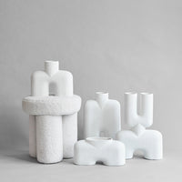 "Set of textured white vases in modern shapes, featuring smooth and rough patterns for a stylish display."