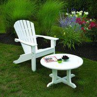 White Adirondack chair and round table set against a vibrant garden with green grass and colorful flowers.