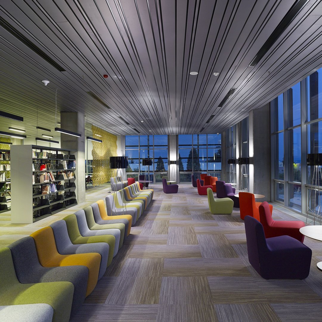Modern lounge featuring multicolored seating in shades of purple, yellow, and red, with sleek wooden flooring.