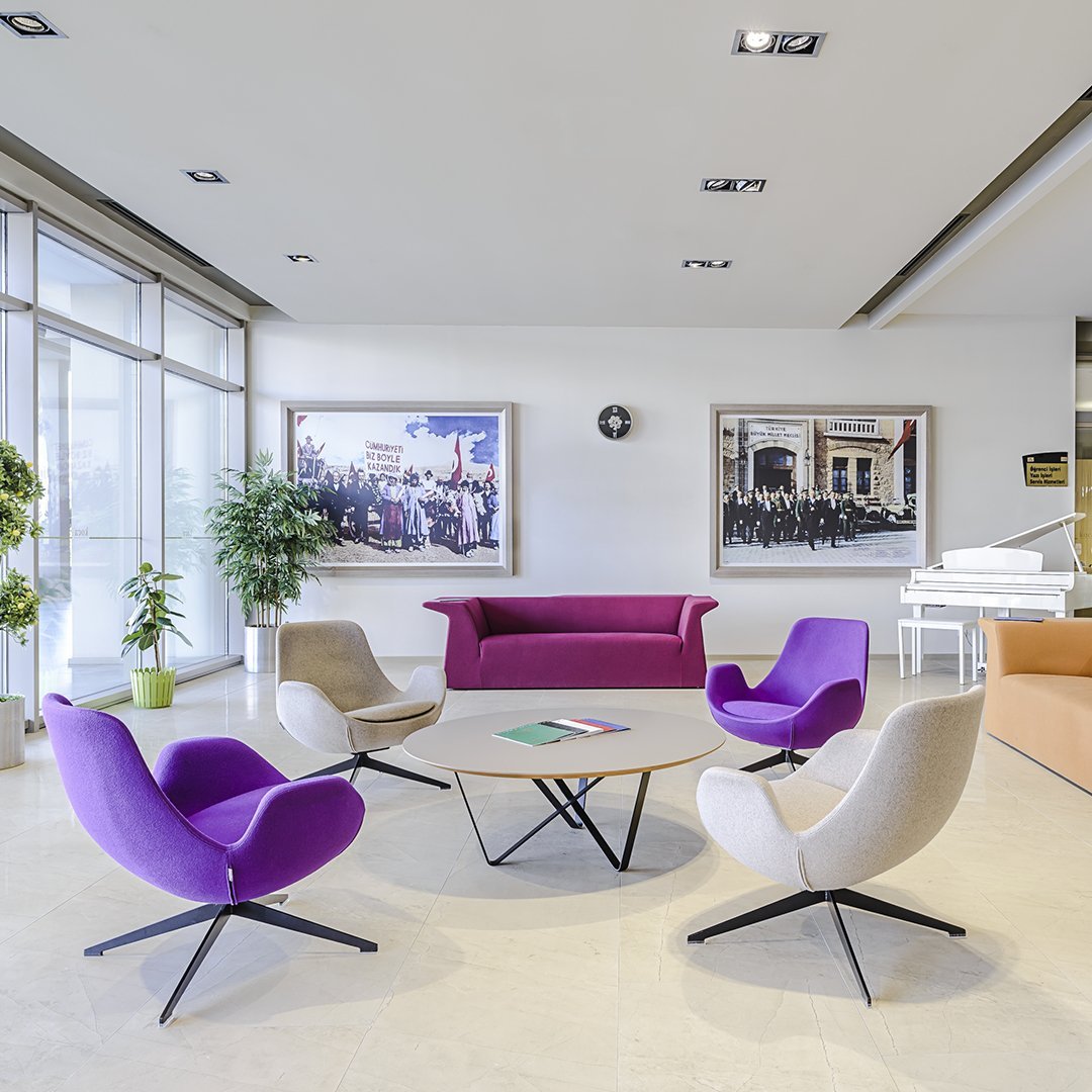 Purple and beige chairs arranged around a round table in a modern, stylish office setting.